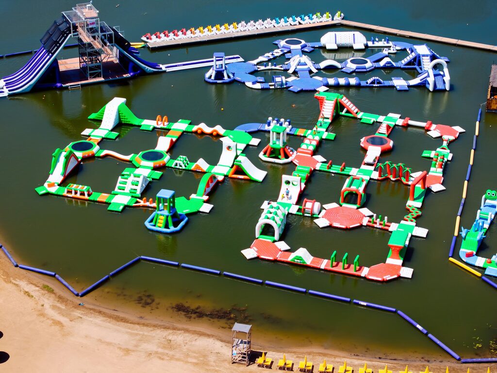 Parcours gonflables du parc aquatique bordés par la plage de sable et ses transats