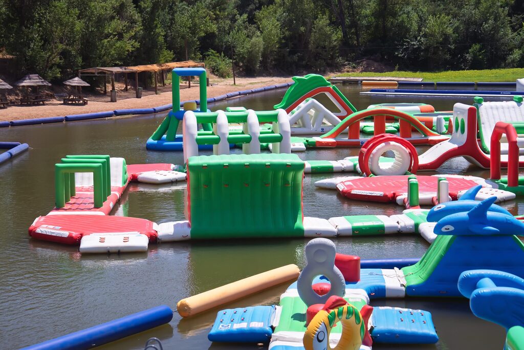 Le parc aquatique gonflable vu depuis l'eau, paillotes de la plage en fond